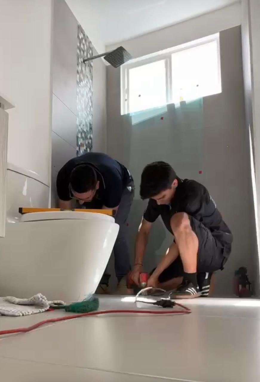 Dos técnicos ajustando una instalación de baño